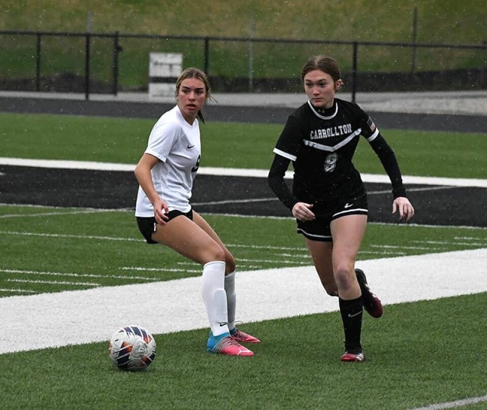 CCM/Dan Ries Carrollton’s Erica Brown (black uniform) battles the Quakers’ Hannah Smith for the ball during a sectional contest Saturday at Carrollton.
