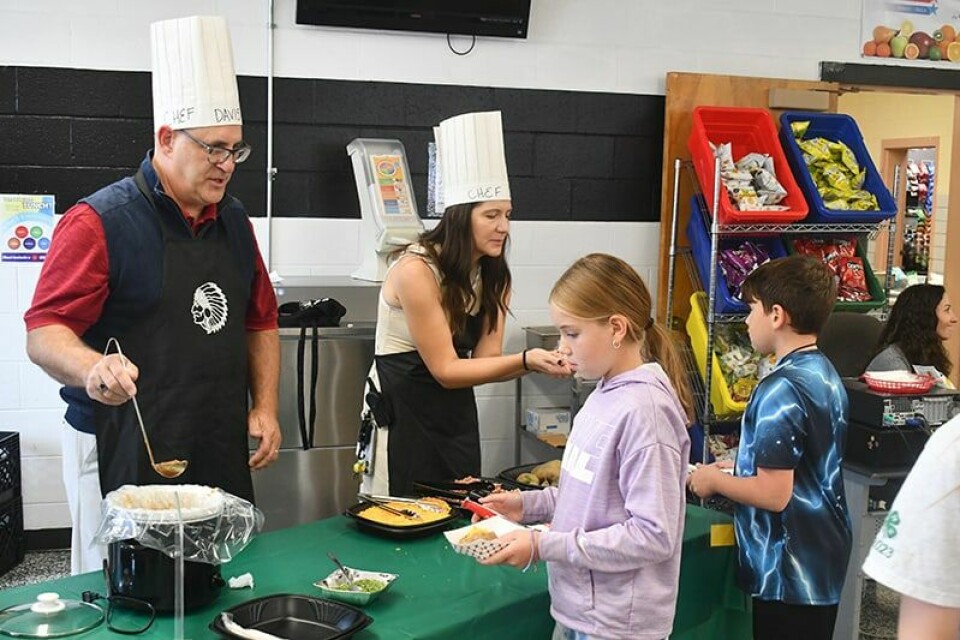 CCM/Dan RiesCarrollton Superintendent Dave Davis (left) and Elementary Principal Holly Dodd assists students Bay Mulheman (left) and Tegan Gibson select toppings for their baked potato.