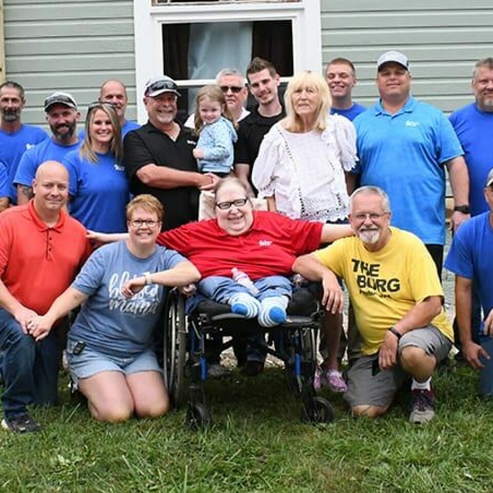 CCM/ Carol McIntireWindow World employees (blue shirts) donated their time to install 21 new windows in the home of Joy Knox and Jeanne Zinda Sept. 9. The group, along with Window World owner Pat Moran (black shirt, holding his granddaughter Emma), and company representatives, are shown with Amsterdam Mayor Jim Phillips, his wife, Jamie, Jeanne Zinda, Rev. David Guess (front from left) and Joy Knox (standing, white shirt).