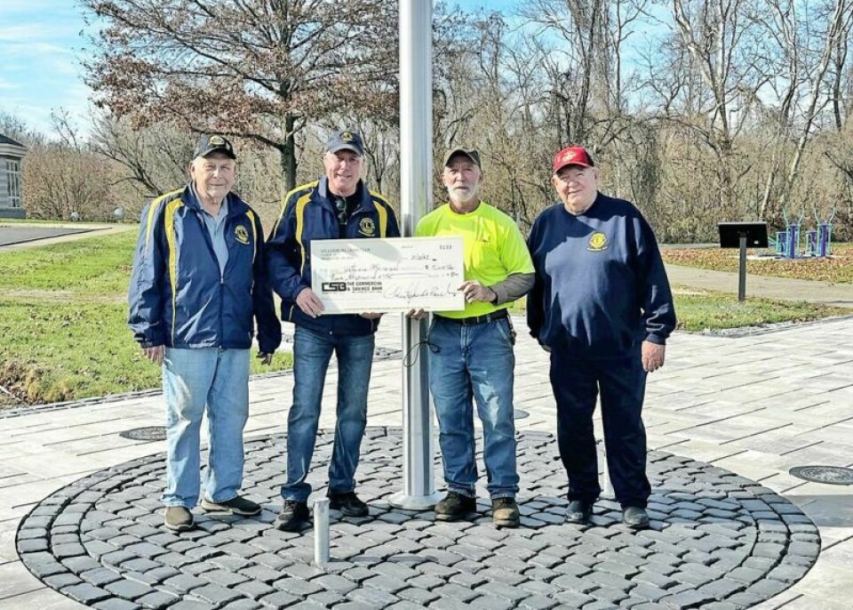 Millersburg Lions Club members Ed Dye, left, Frank Arnold and Ray Beck presented Millersburg Veterans Monument committee member Jim Miller, in yellow, with a check for $5,000 on Thursday, Nov. 16 at the site of the monument that will be dedicated to U.S. military members who were MIA, KIA or POW. Millersburg Lions support veterans monument effort