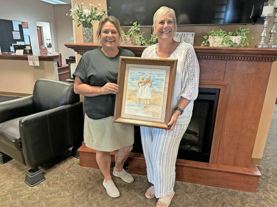 Elaine Booth, left, and Jamie Smith hold a painting by Rosemary Hall of Dover that was a gift to Smith at the senior center last year. Artists sought for first show at the Tuscarawas County Senior Center