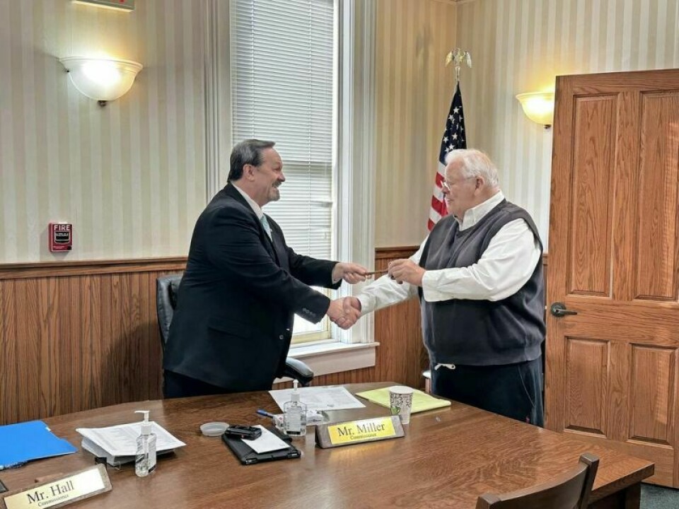 Commissioner Dave Hall, left, accepts the commissioner’s chair gavel from outgoing commissioner chairman Joe Miller during the recent commissioner meeting on Jan. 8. Hall accepts Holmes commissioner chairman role