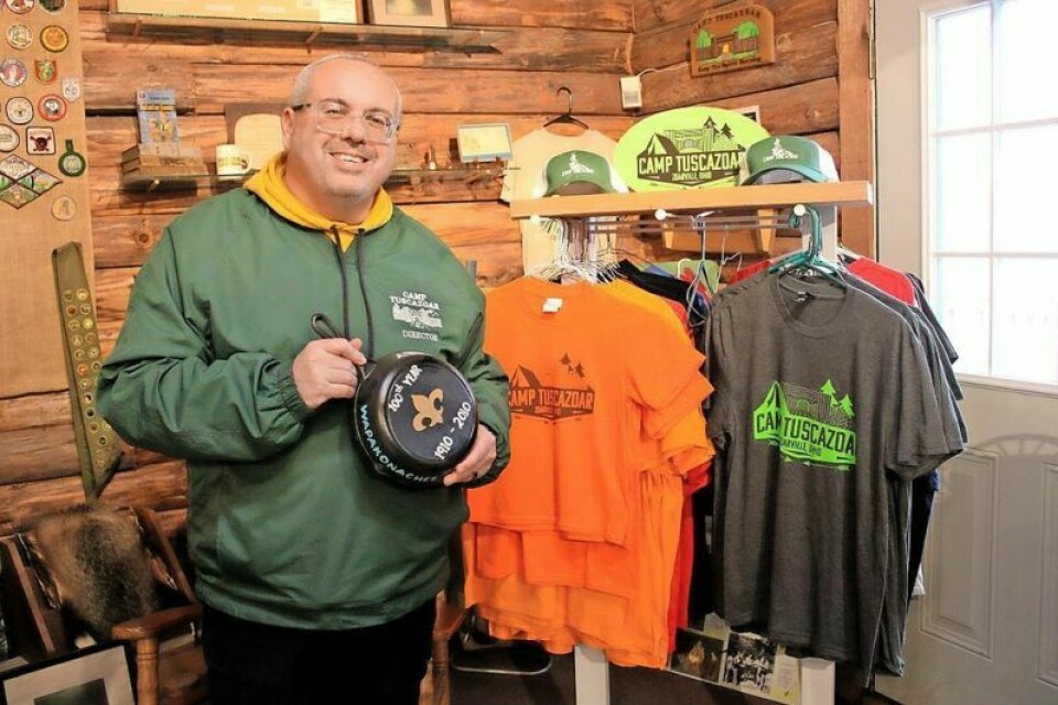 Seth Arkow, a director at Camp Tuscazoar, shows off one of the frying pan trophies given to the winning team of the Gold Rush. Also shown are some of the Camp Tuscazoar shirts available for purchase at the camp store. Gold Rush to be held at Camp Tuscazoar