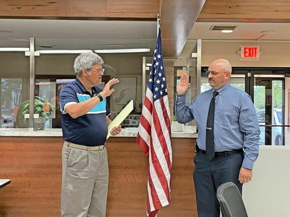 Strasburg Law Director Terry Seeberger, left, stands with Strasburg Fire Chief Jason Ely as he takes the oath of office. Strasburg hires Ely as new fire chief