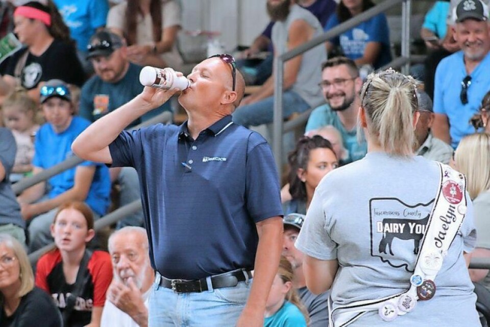 Mike Yoder celebrates a winning bid at the dairy auction by chugging milk. The lot was purchased by Gerber & Son’s, Beck’s Seed and KLA (Kolt Andreas) Farms. Fair sales support 4-H members and community