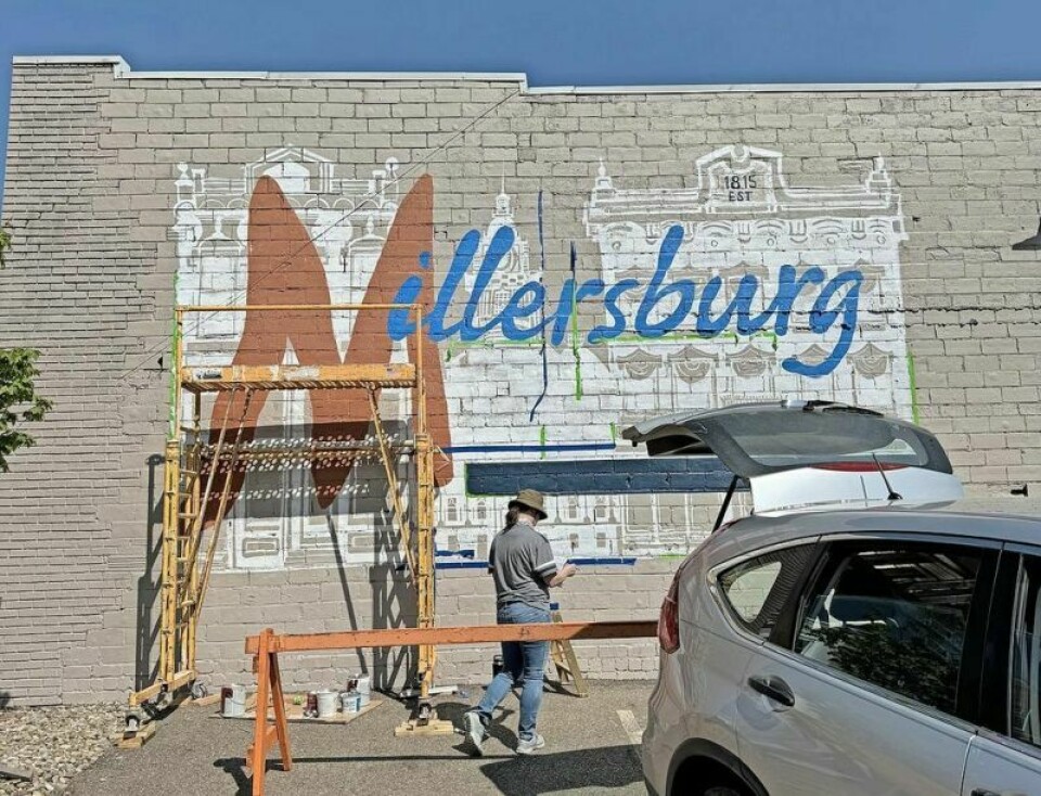 Marlea Leinbach works on the new mural that helped beautify the west edge of Historic Downtown Millersburg. New HDM mural greets travelers from the west