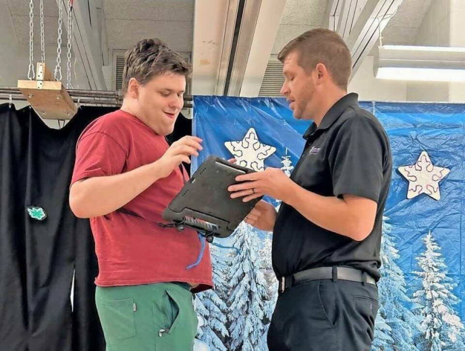 Grant Fox, right, an intervention specialist at Holmes County Board of Developmental Disabilities School, and his student Colin Spangler stand on the stage for the school's Christmas program last December. Spangler used his communication device to serve as the narrator for the program. Holmes County BDD School helps special needs children thrive