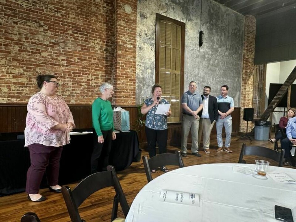 Led by Tiffany Gerber, left, Holmes County Chamber executive director, and Shasta Mast, Holmes County Education and Community Foundation director, with a microphone, the chamber board honored Leah Miller for her many years of dedication to the Leadership Holmes County program during a celebration on May 7. Leah Miller honored as she steps away from LHC