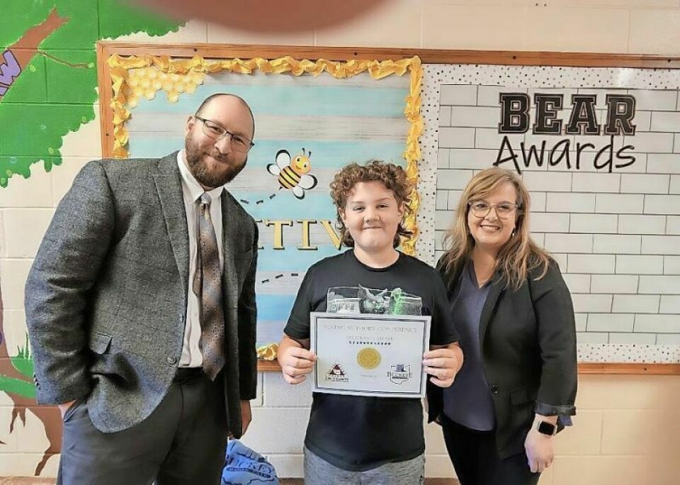 Andrew Johnson, left, of Tri-County ESC and Kimberly Jarvis, right, executive director of the Buckeye Book Fair, flank Julian Uhler, a sixth-grader from Holmesville Elementary and one of the 10 students selected by their respective schools to receive the Young Authors Conference Excellence Award. Over 400 students attended the Young Authors Conference on Nov. 3. Young Authors Conference draws over 400 students