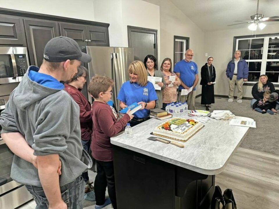 Holmes County Habitat for Humanity Executive Director Mary Neutzling presents each of the Whitman family members with their own personal Bibles. While Habitat is a Christian organization, its members never try to force any beliefs on its families. Holmes Habitat dedicates home of the Whitman family
