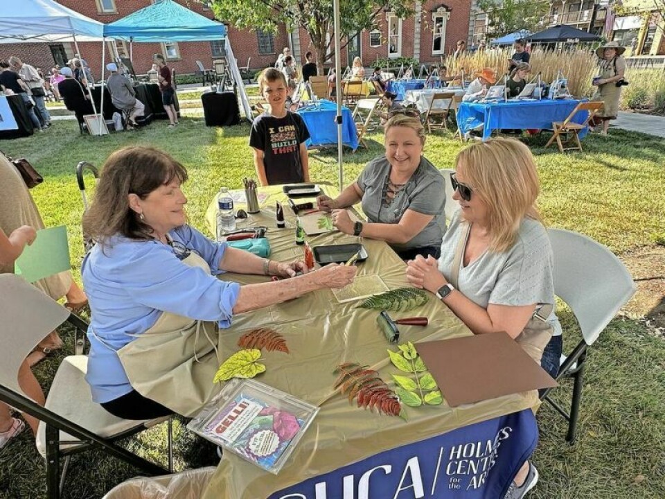 Holmes Center for the Arts teacher Karen Drongkowski, left, takes a visitor to Arts in the Burg through the steps of the art form of Gelli leaf painting. HCA highlights Arts in the Burg experience