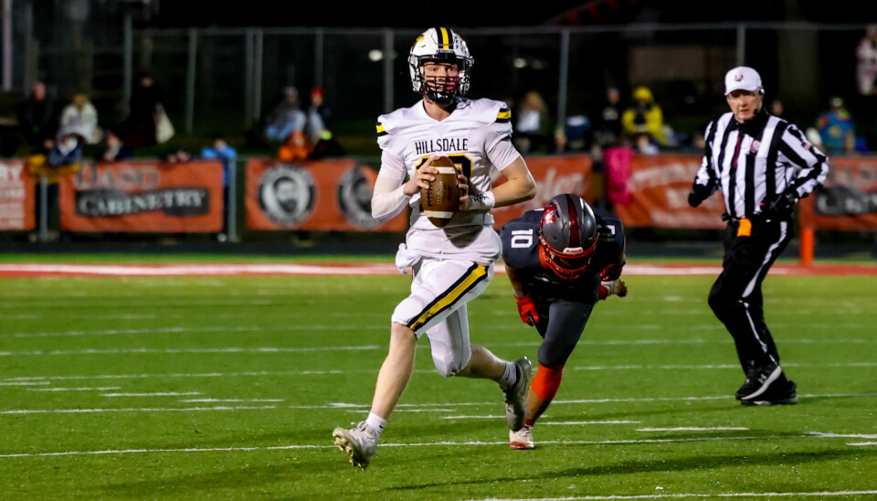 Hillsdale quarterback Kael Lewis looks to escape pressure from Norwayne's Ryder Ingold during their battle tonight.